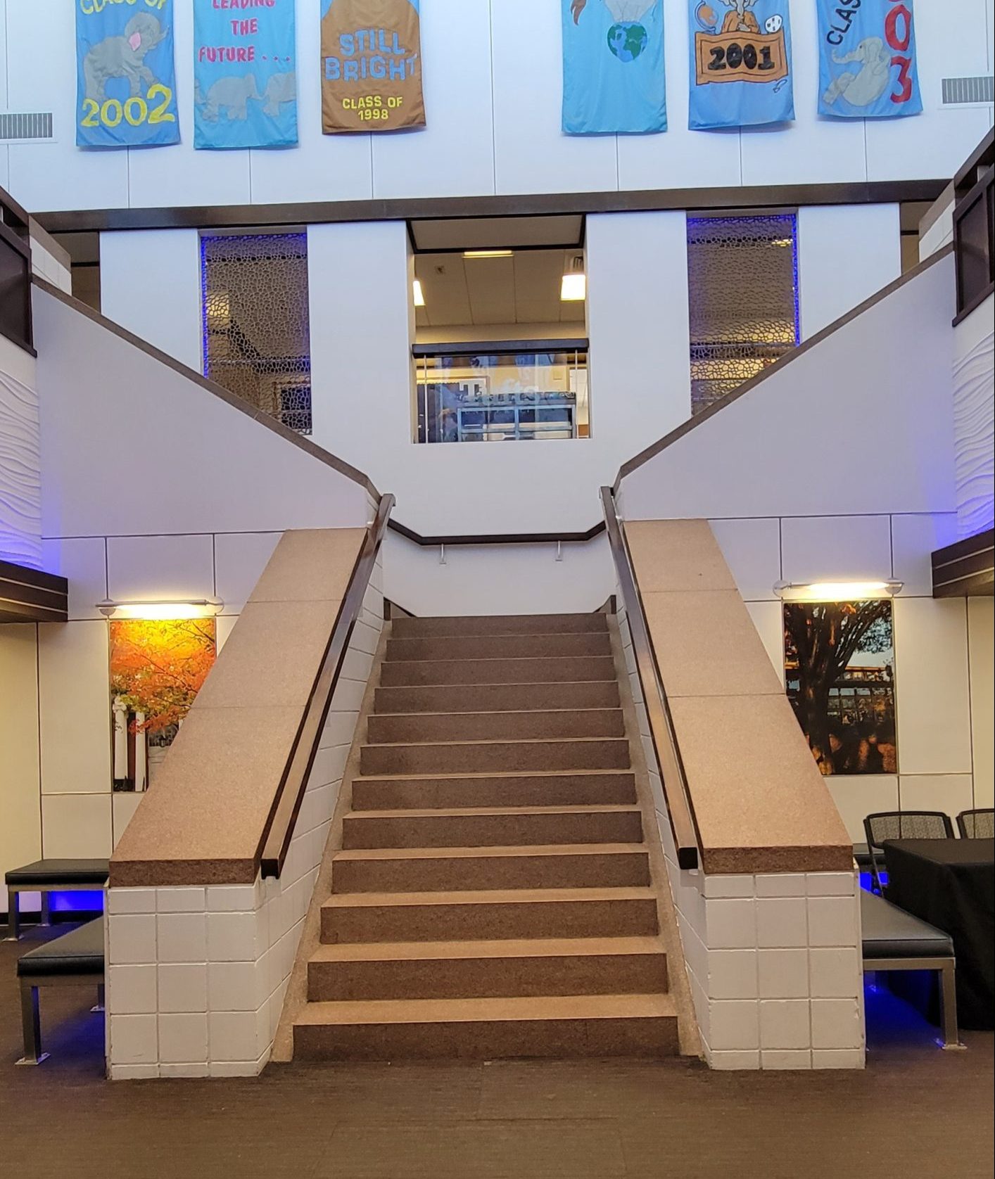 Wide stairs that split left and right at the top. Tufts banners hang on the wall above.