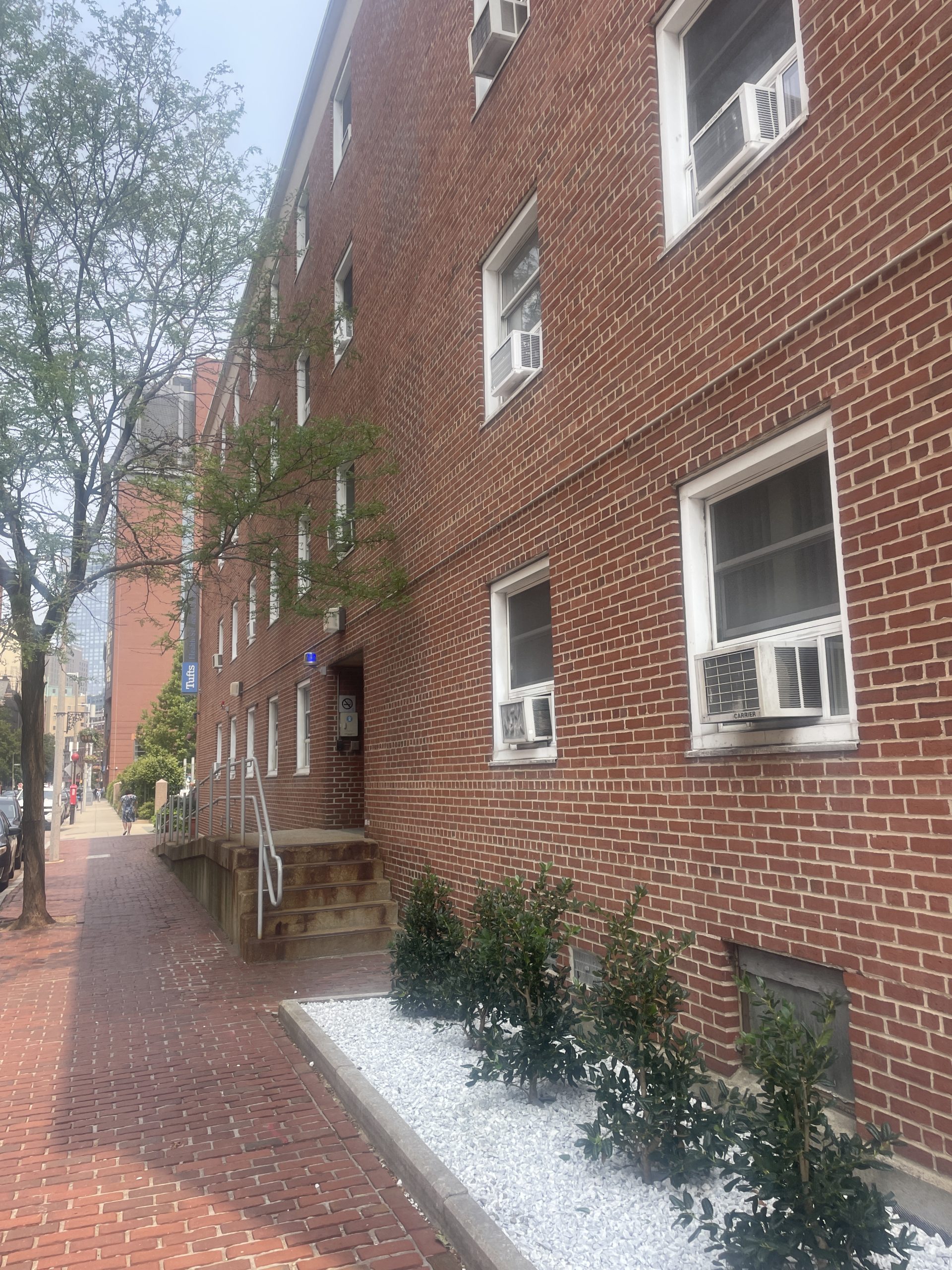 Brick building on a city block with a staircase leading up to the top of ramp